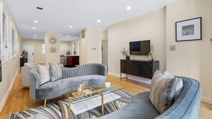 A modern living room with a grey sofa, a glass coffee table, and a flat-screen TV on a black cabinet. - 6BD/5BTH + Roofdeck - Downtown Chicago! (Chicago)
