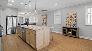 A modern kitchen with a central island, stainless steel appliances, pendant lighting, and a dog-themed artwork on the wall. - 6BD/5BTH + Roofdeck - Downtown Chicago! (Chicago)
