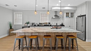 A modern kitchen with a large island, bar stools, stainless steel appliances, and pendant lighting. - 6BD/5BTH + Roofdeck - Downtown Chicago! (Chicago)