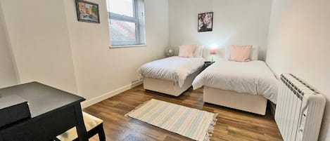 Et lille, godt oplyst soveværelse med seng, natbord og radiator.