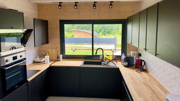 Una cocina moderna con un ventanal grande, electrodomésticos integrados y vistas al exterior.