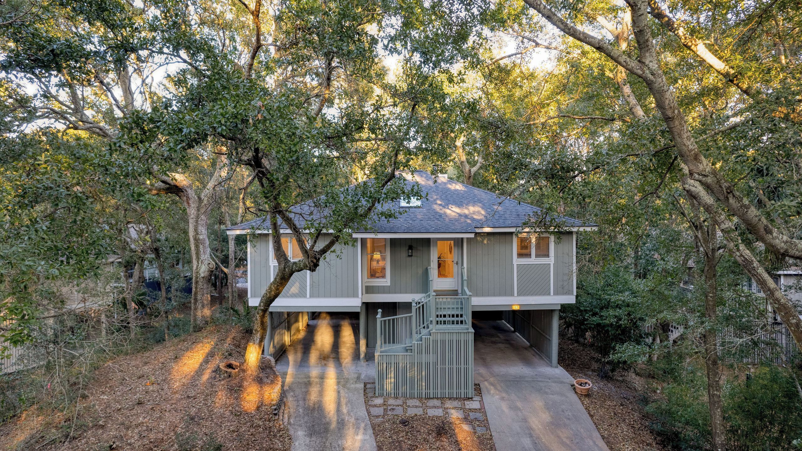 Una casa a due piani con un portico, circondata da alberi.