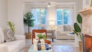 A living room with a sofa, armchair, coffee table, and a fireplace. - Conch Cottage by Avantstay Walk to Beach, Deck, Fireplace, Outdoor Dining (Isle of Palms)