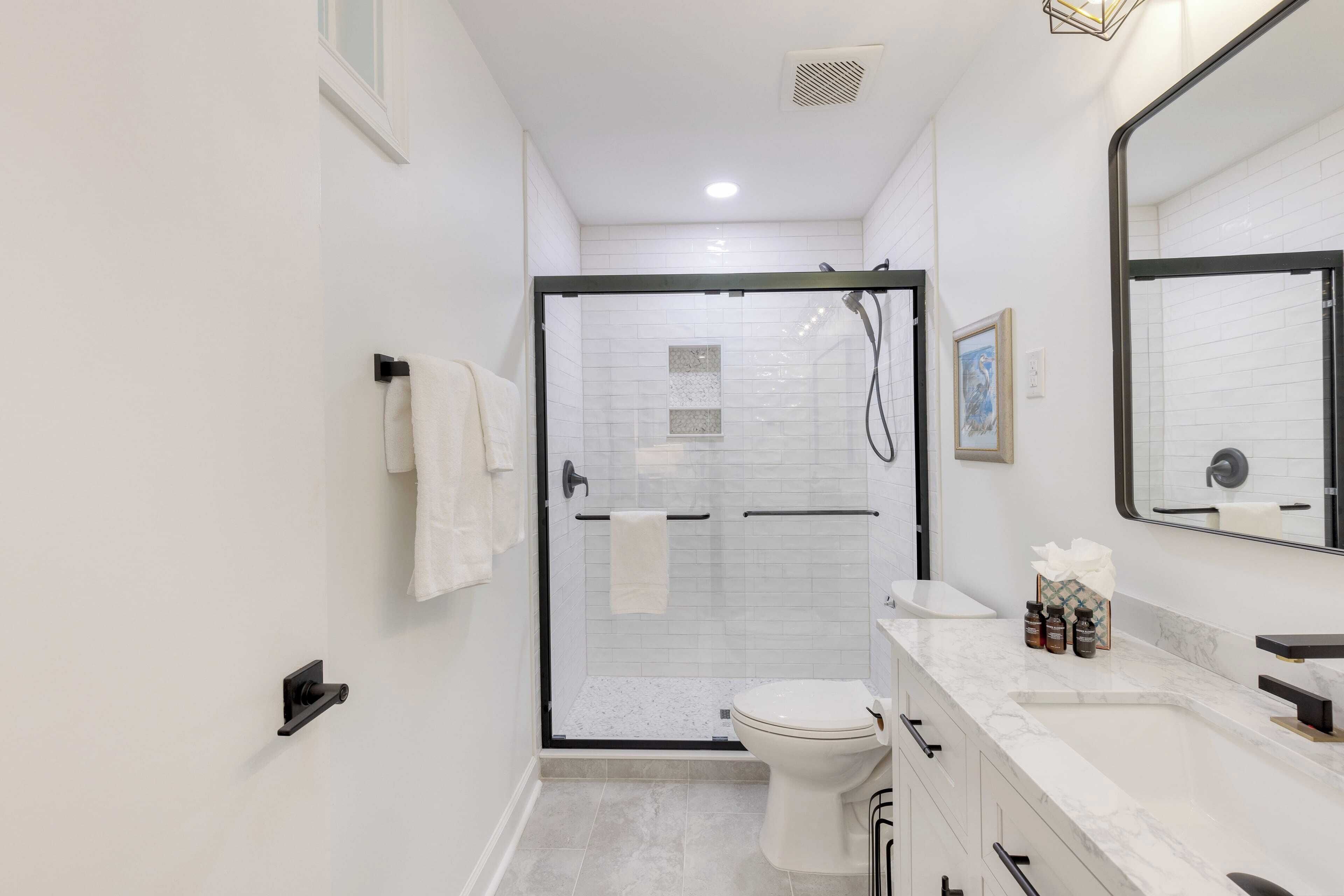 A modern bathroom with a glass-enclosed shower, a white toilet, and a marble sink.