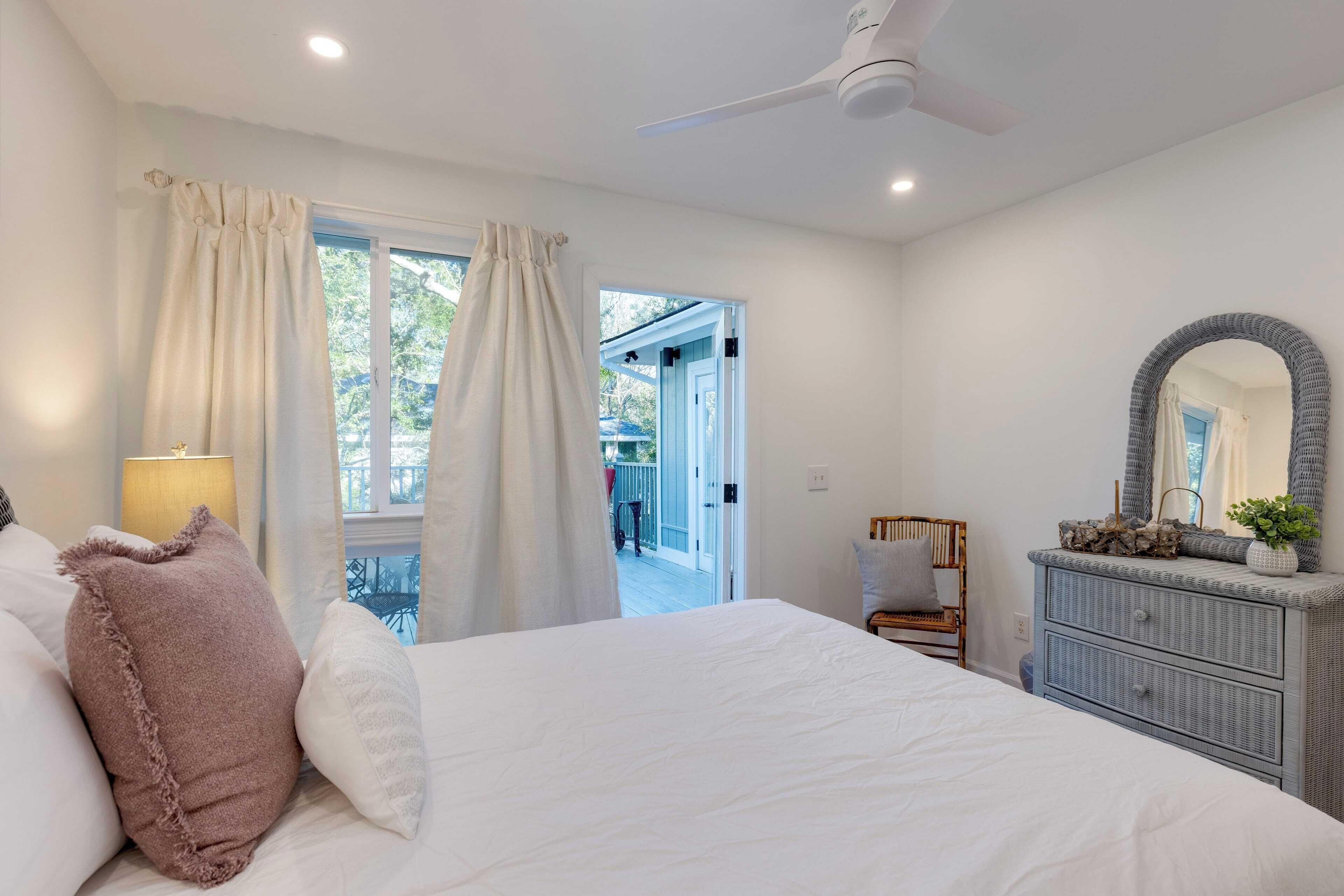 A bedroom with a bed, a dresser, a mirror, and a window with curtains.