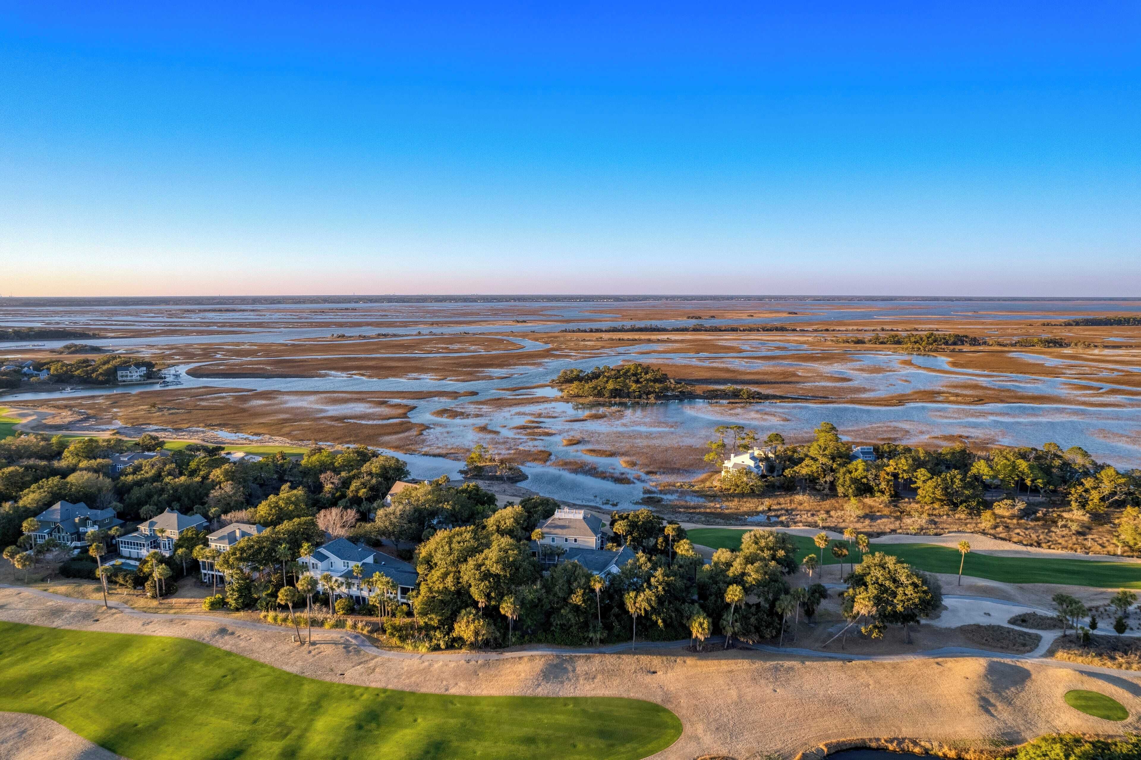 Luftaufnahme eines Küsteneigentums mit Golfplatz, Sandflächen und einem großen Gewässer.