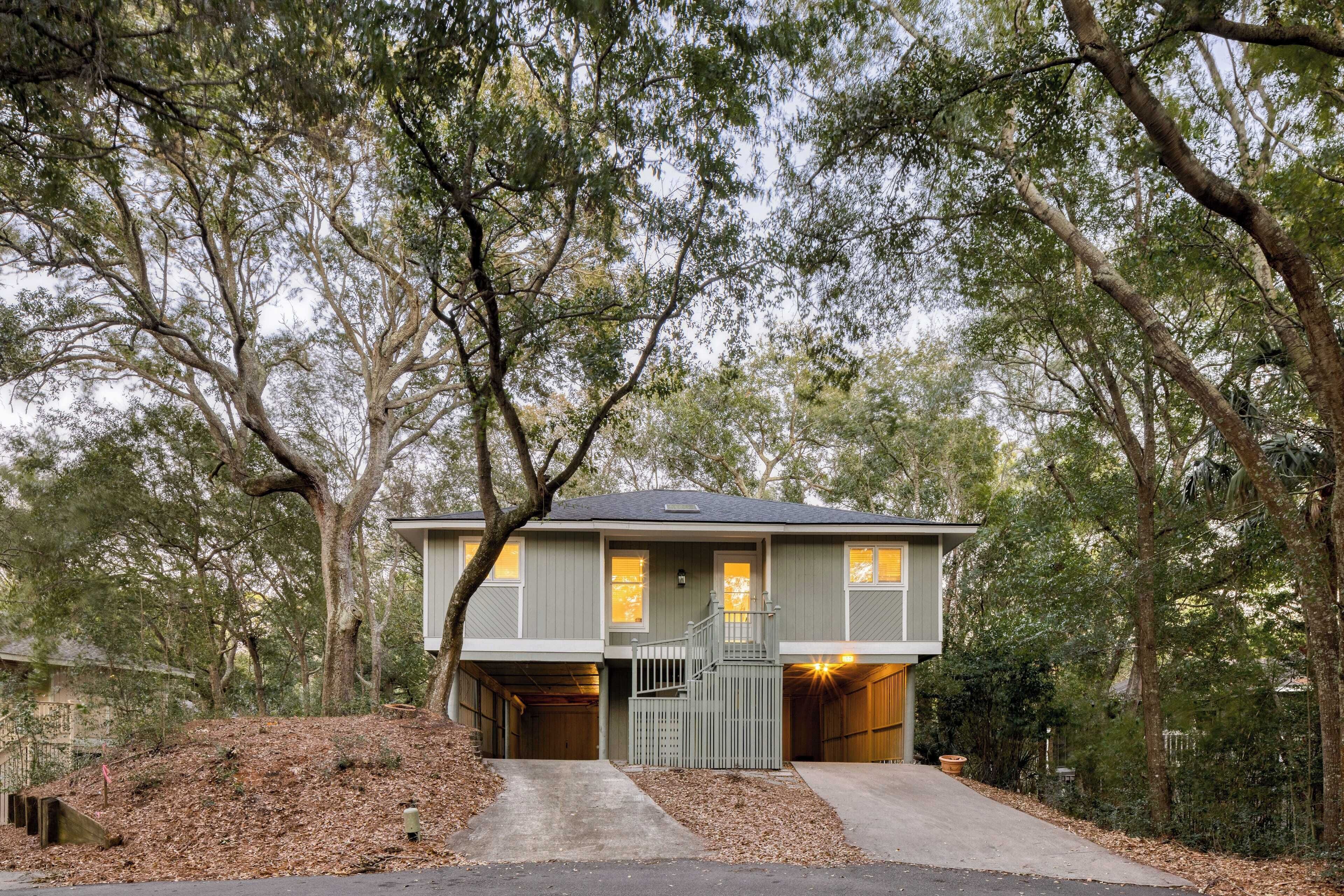 A two-story house with a covered garage, surrounded by trees.