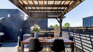 A covered outdoor patio with a wooden table and chairs, a flower vase, and a grill area. - Huge Private Rooftop Deck w/ Firepit + Putt-putt 8 Mins to Broadway Doralee (Nashville)
