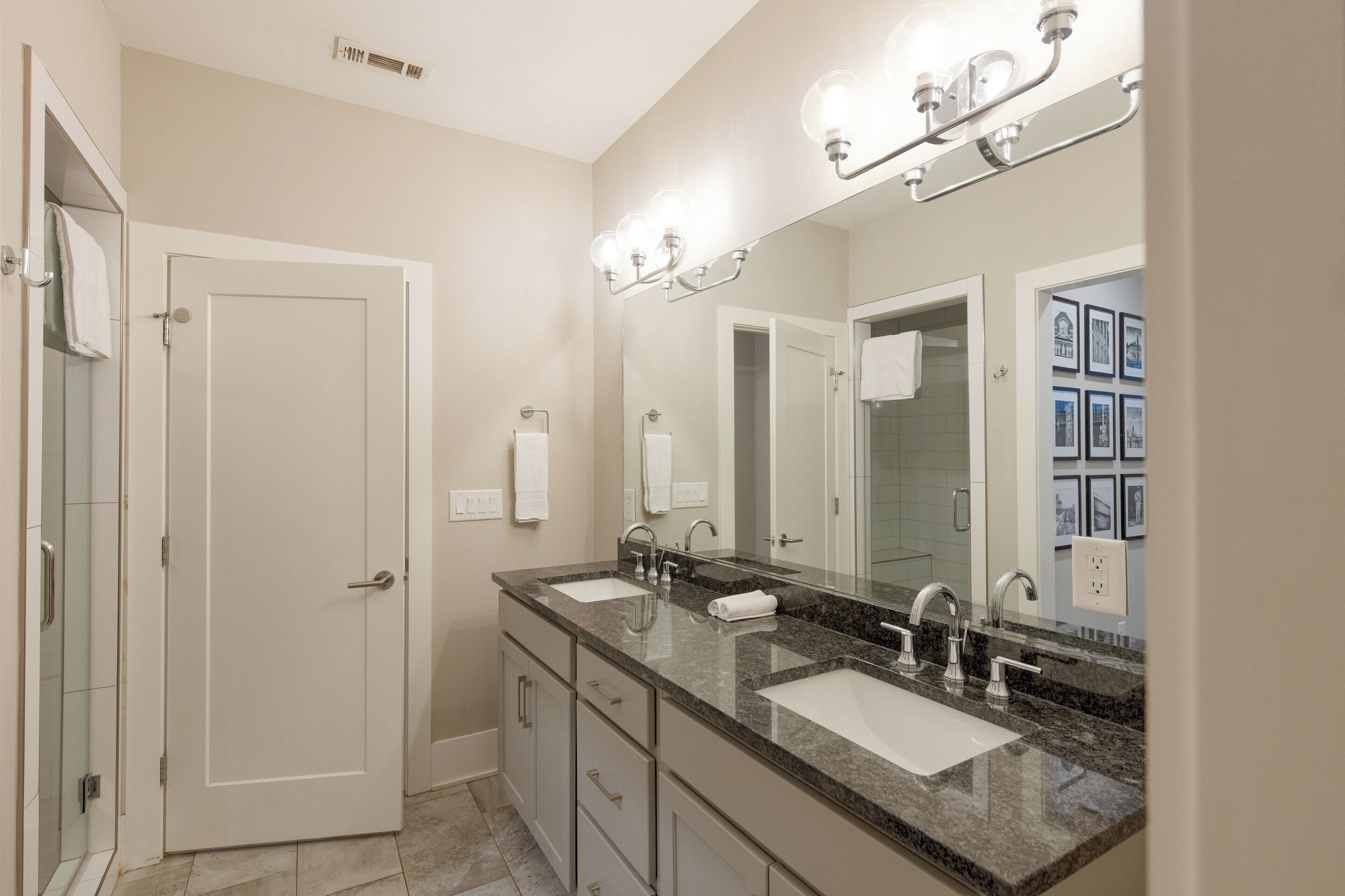 A bathroom with two sinks, a large mirror, and a shower.