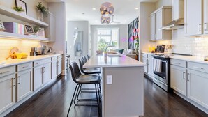 A modern kitchen with a central island, white cabinetry, and a large pendant light. - Huge Private Rooftop Deck w/ Firepit + Putt-putt 8 Mins to Broadway Doralee (Nashville)