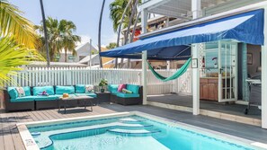 A pool area with a white fence, a blue canopy, and a pool with steps. - Prime Old Town Location w/ Pool, Walk to Duval Steet Blue Heron by Avantstay (Key West)