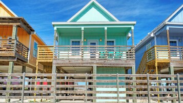 A beachfront property with multiple wooden structures, each featuring a balcony and a small porch.