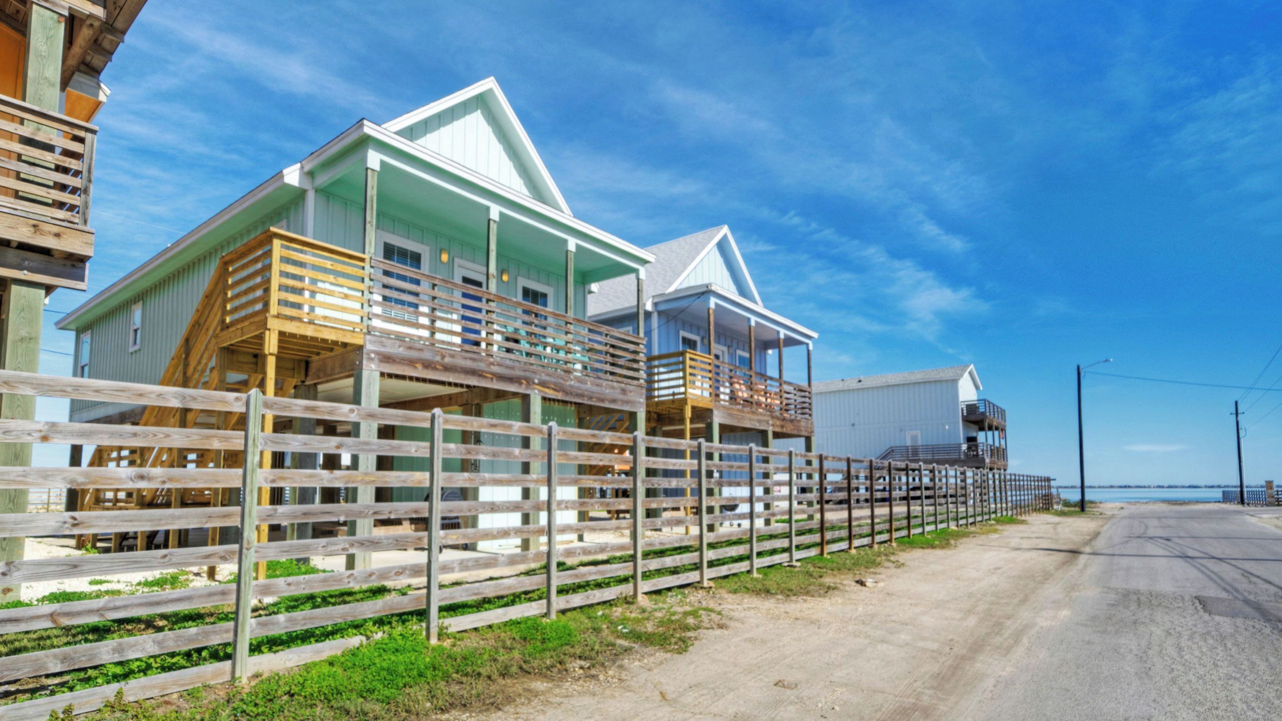 Un bâtiment situé sur la côte, doté de nombreux balcons, d’une clôture en bois et offrant une vue dégagée sur l’océan.