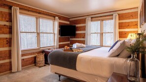 A bedroom with a bed, a flat-screen TV, wooden walls, and large windows with blinds. - Twilight Ridge by Avantstay Mountain Mansion, 20min to Pigeon Forge (Sevierville)