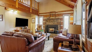 A cozy living room with a fireplace, leather sofas, a television, and a stone wall. - Twilight Ridge by Avantstay Mountain Mansion, 20min to Pigeon Forge (Sevierville)