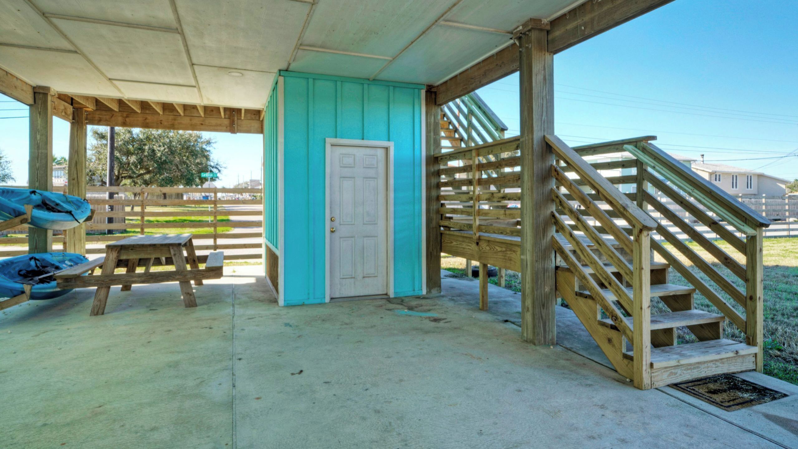 A covered outdoor area with a wooden staircase, a door, and a picnic table.