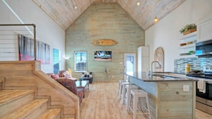 Una cocina amplia con suelo de madera, una isla central y vista a la playa por una ventana.