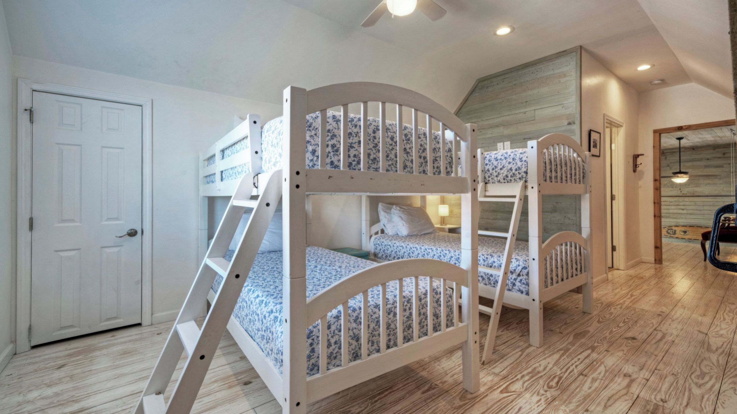 Ein Zimmer mit Etagenbetten, einer Tür, einer Treppe und Holzboden.