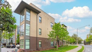 A modern building with large windows and a flat roof, surrounded by a well-maintained lawn and a sidewalk. - Music Row w Free Parking  Close to University (Nashville)