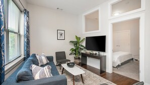 A modern living room with a sofa, a coffee table, a TV, and a plant. - Music Row w Free Parking  Close to University (Nashville)