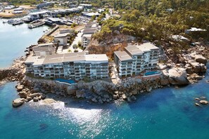 Un hôtel situé sur la côte, composé de plusieurs bâtiments, avec un rivage rocheux et une eau d’un bleu cristallin.