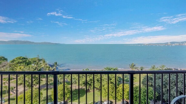 En balkon med udsigt over et roligt hav og fjerne bjerge.