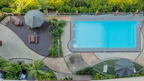 Oversigtsbillede af et poolområde med terrasse, liggestole og parasoller.