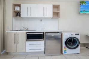 A compact kitchen with a built-in oven, a refrigerator, and a washing machine.