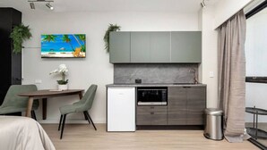 A compact hotel room with a kitchenette, a dining area, and a bed.