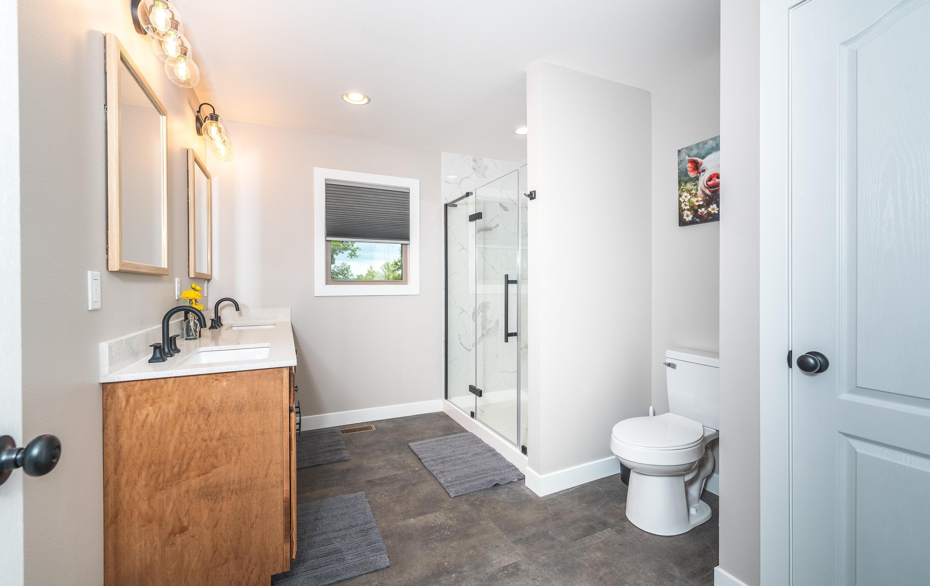 Een moderne badkamer met een houten wastafelmeubel, een douchecabine met glazen wanden en een wit toilet.