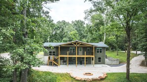 A two-story building with a balcony, surrounded by trees and a gravel driveway.