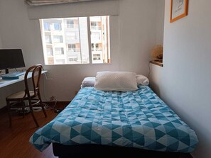 Cozy bedroom with a single bed, desk, and window offering a view of the outside.