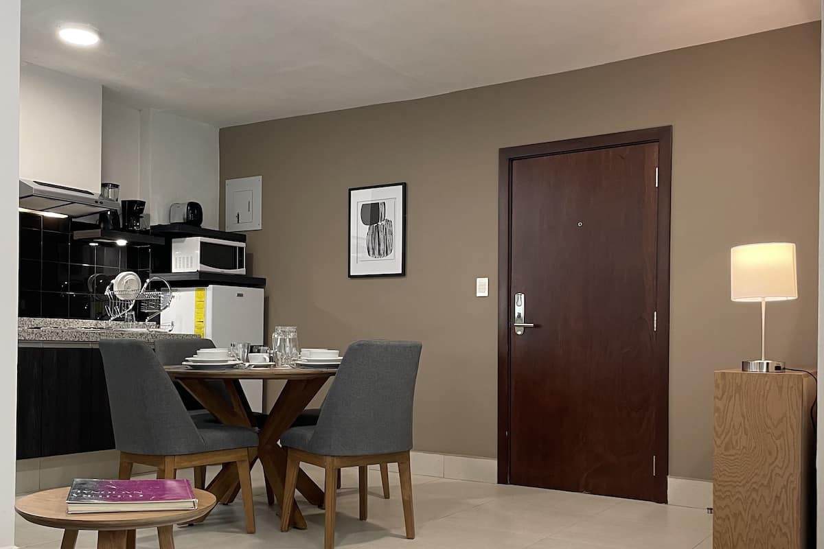 A modern kitchen with a dining area, a wooden door, and a lamp.
