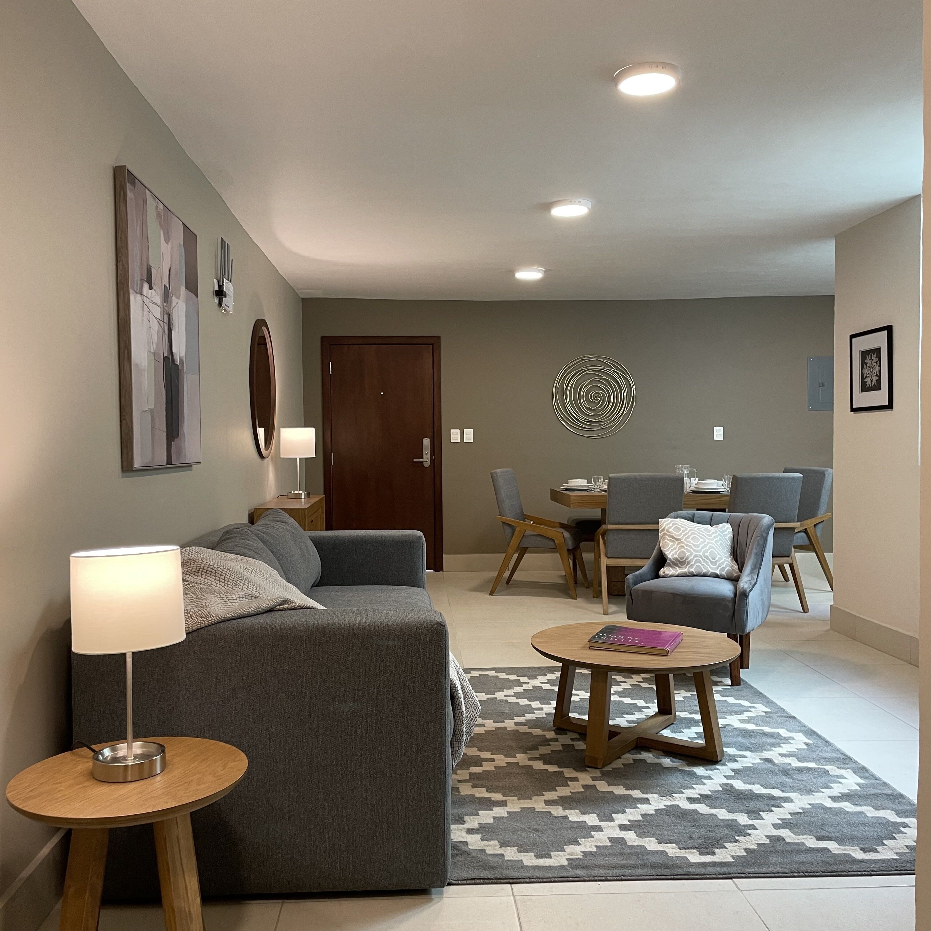 A modern living room with a gray sofa, a round coffee table, and a dining area with a gray dining table and chairs.