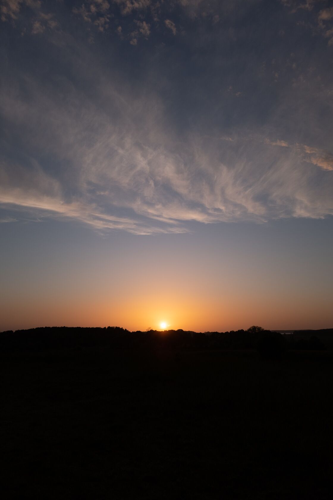 A sunset over a silhouette of a landscape.