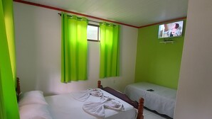 A room with a single bed, a smaller bed, green curtains, a TV on the wall, and a window with blinds. - Pousada Sítio Monte Sinai (São José do Barreiro)