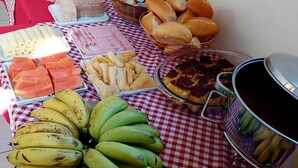 A buffet table with various food items including bread, pastries, and fruits. - Pousada Sítio Monte Sinai (São José do Barreiro)