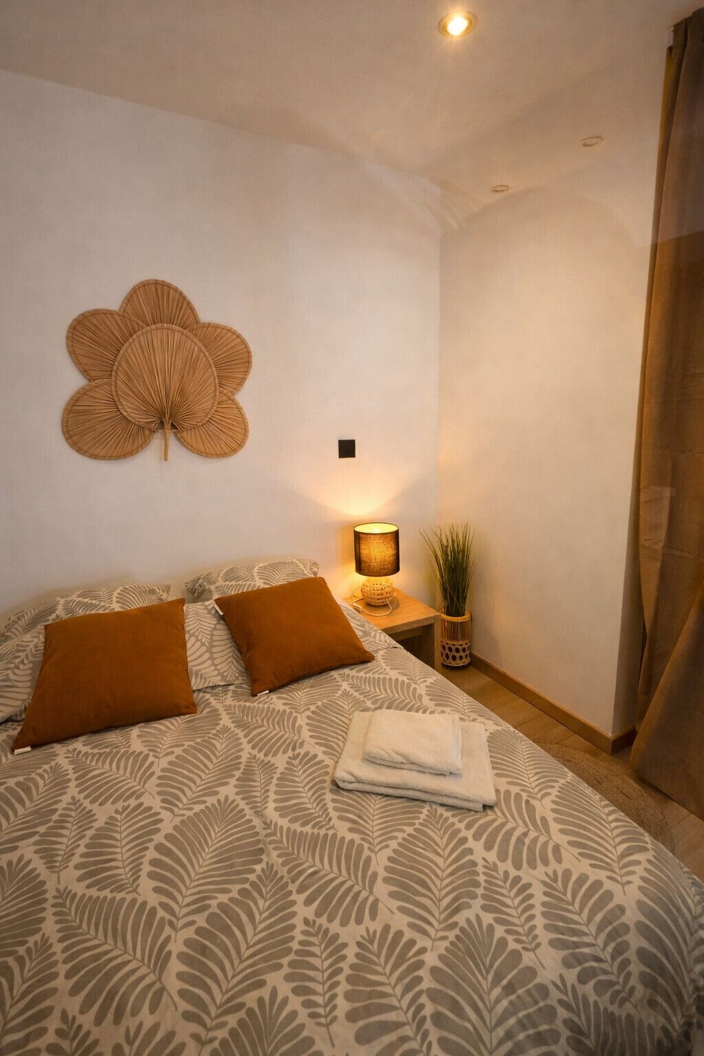 Une chambre à coucher avec un lit, des oreillers, une lampe de chevet et un élément de décoration murale.