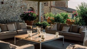 An outdoor seating area with a wooden table, two sofas, and potted plants. - Villa Stellina - Private Tuscan villa with pool (Tavarnelle Val di Pesa)
