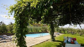 A pool area with stone flooring, a table with chairs, and a pergola with climbing plants. - Villa Stellina - Private Tuscan villa with pool (Tavarnelle Val di Pesa)