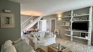 A spacious living area with a white sofa, a coffee table, and a TV on a white shelf. A staircase leads to an upper level. - Great 4-bedroom villa with heated pool (Duće)