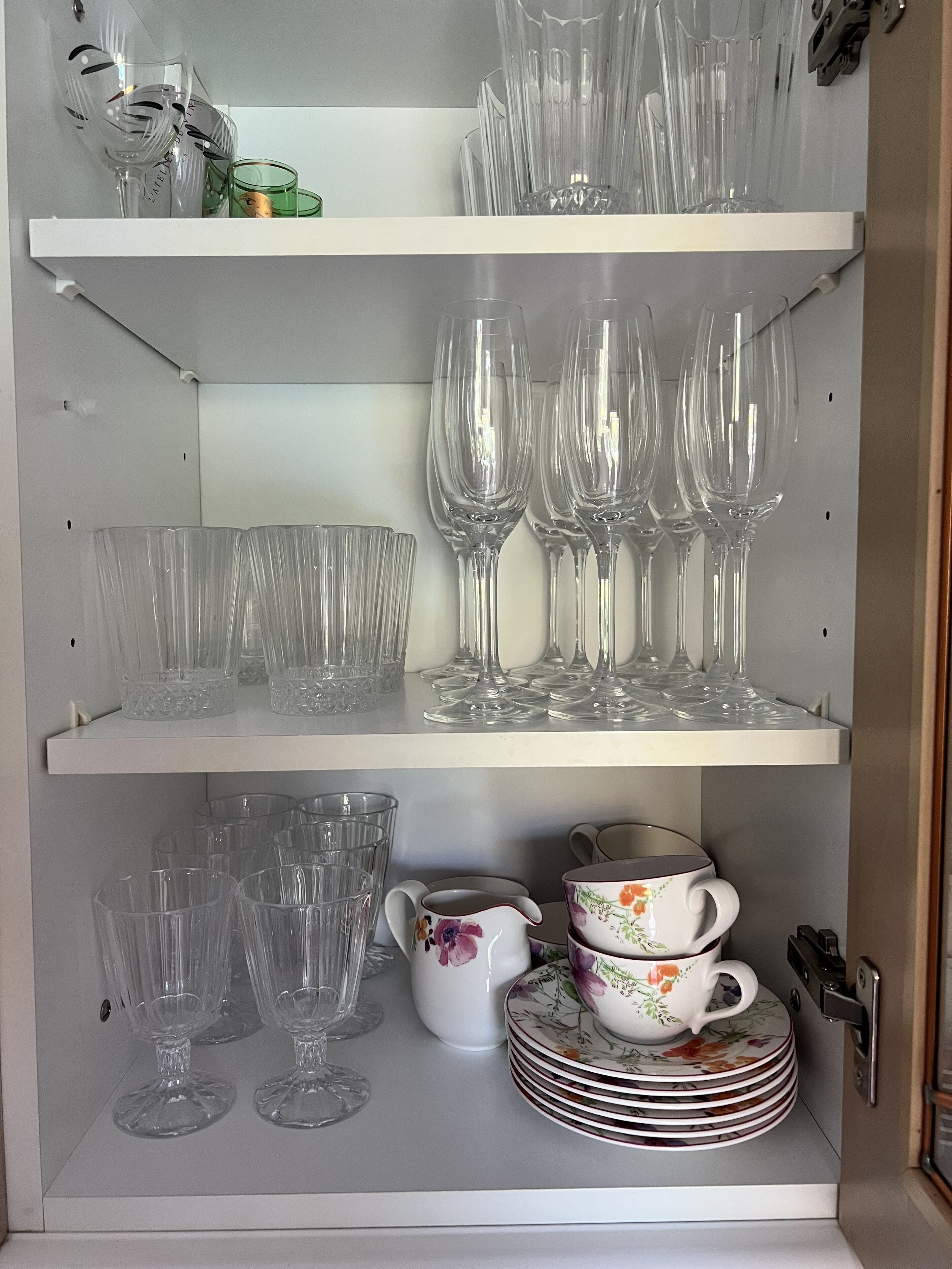 A storage unit with shelves holding various glassware and dishes.