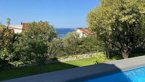 A swimming pool with a view of the sea and buildings in the background. - Great 4-bedroom villa with heated pool (Duće)