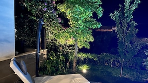 A sunlit outdoor lounge area with two lounge chairs and a small table, surrounded by greenery and a tree. - Great 4-bedroom villa with heated pool (Duće)