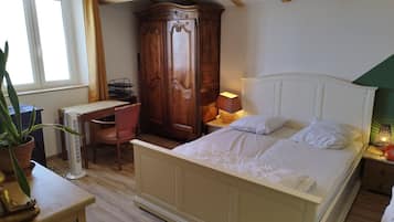 A bedroom with a bed, a desk, a chair, a wardrobe, and a window.
