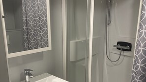 A bathroom with a white sink, a mirror, a shower enclosure, and patterned shower curtains.