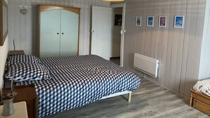A bedroom with a bed, a wardrobe, a radiator, and a ceiling light fixture.