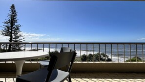 A balcony with a table and chairs overlooking a beach and ocean. - Edgecliffe 3 Kings Beach Unit With Ocean Views (Caloundra)