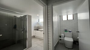 A modern bathroom with a glass shower enclosure, a white sink, and a toilet. - Edgecliffe 3 Kings Beach Unit With Ocean Views (Caloundra)