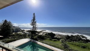 Ein Pool mit Blick auf das Meer und ein Gebäude im Hintergrund.